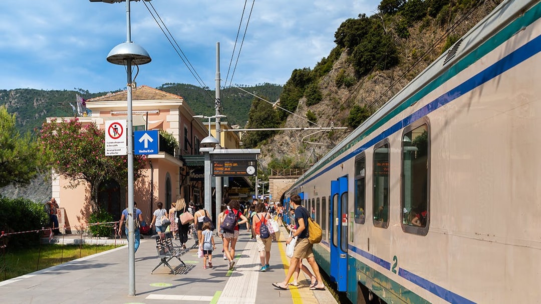 Travelers at a train station in Cinque Terre, Italy, boarding a train.