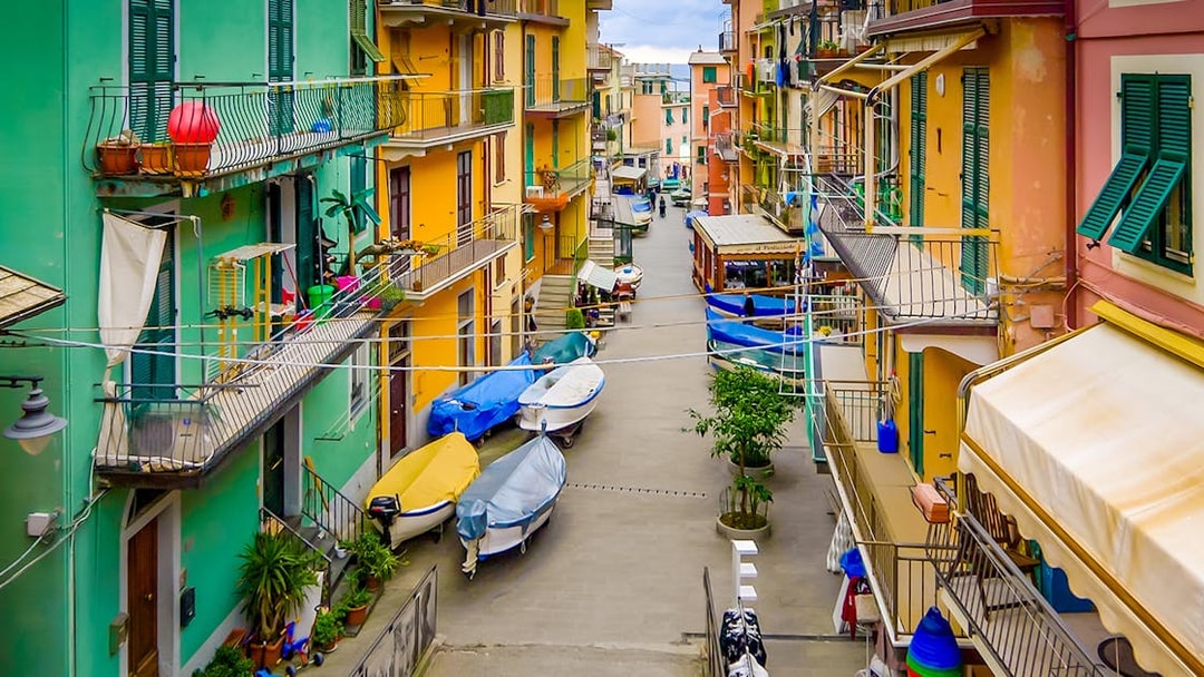 Colorful buildings and boats in a narrow street of Cinque Terre, part of Florence to Cinque Terre tour.