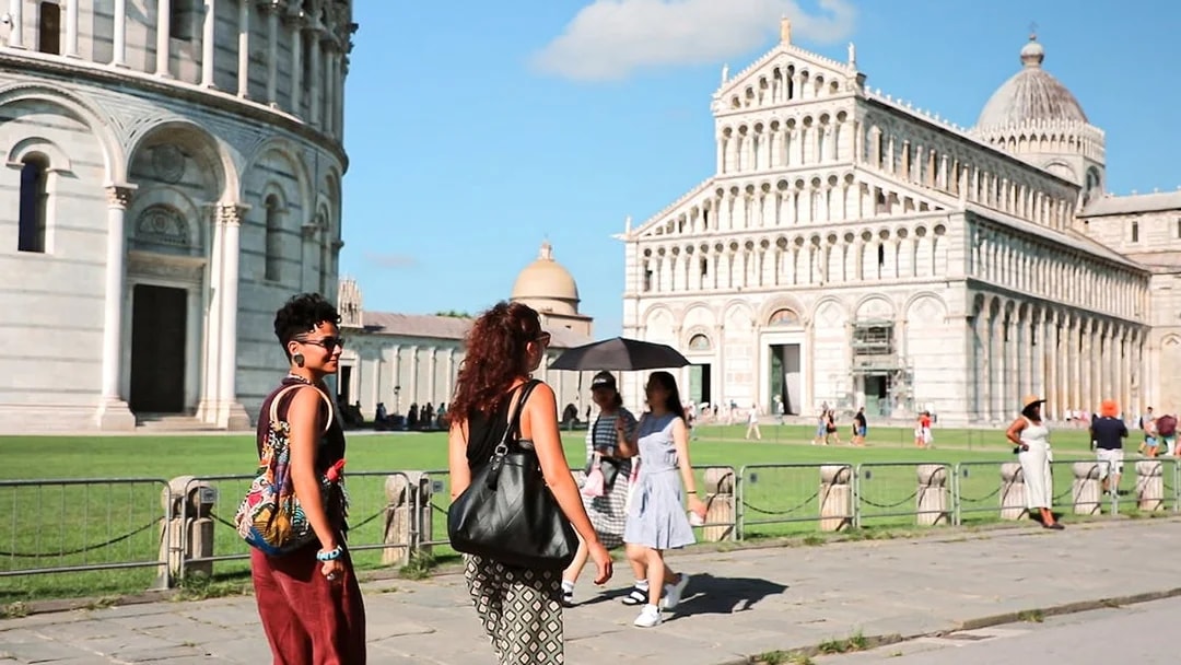 Tourists walking near Pisa Cathedral on a guided tour from Florence.