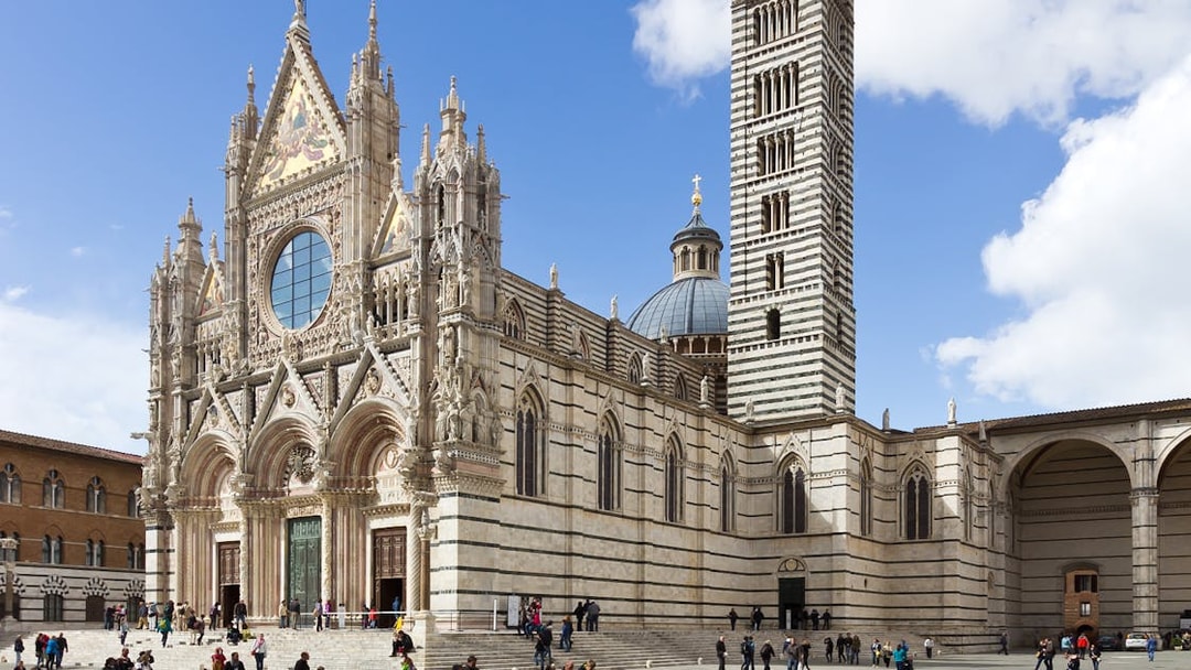 Siena Cathedral facade with visitors in Tuscany, Italy.