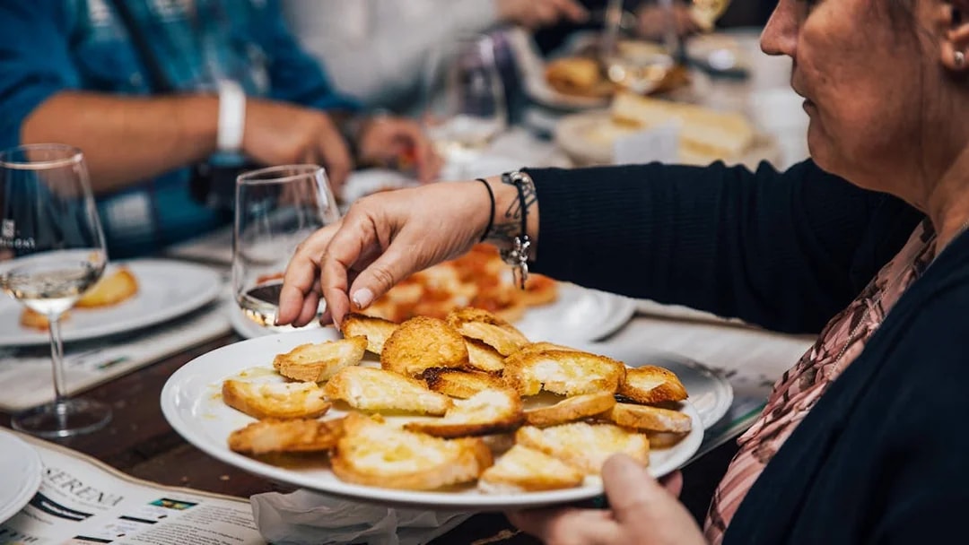 Person serving bruschetta during a Tuscany food tour.