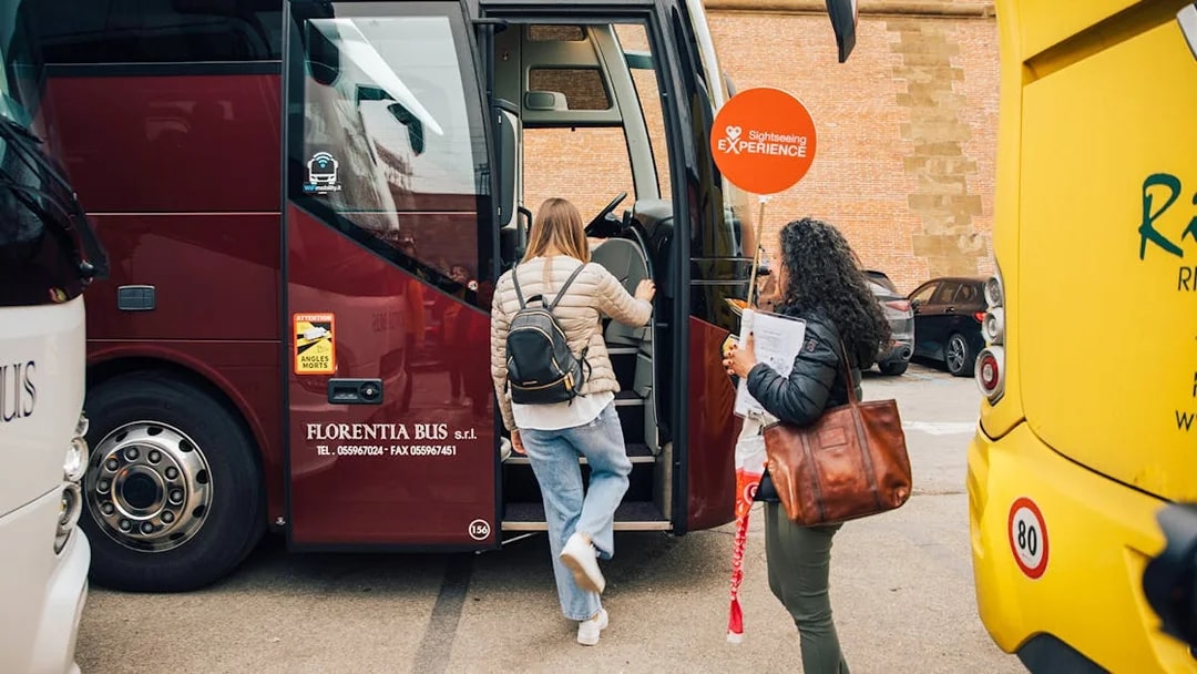 Tourists boarding a bus for the Tuscany in a Day tour, visiting Siena, San Gimignano, and Pisa.