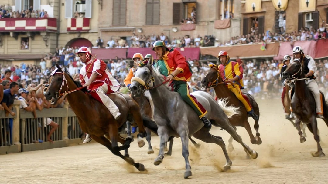 Horse race at Siena's Palio, Tuscany, with riders in colorful attire.