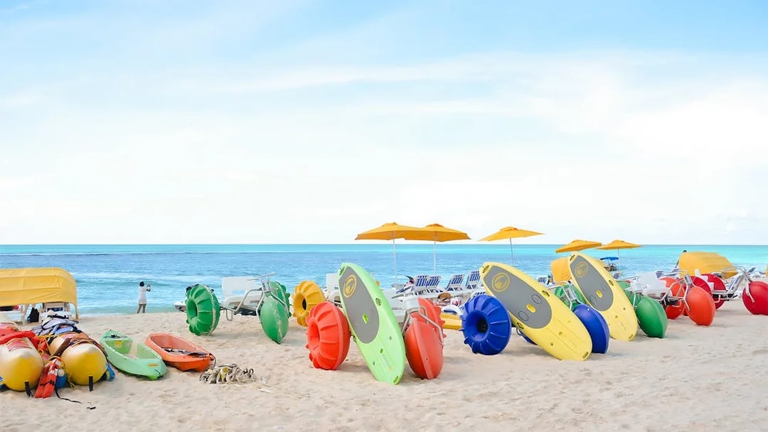 Colorful kayaks and water bikes on a sandy beach in Bimini, Bahamas.
