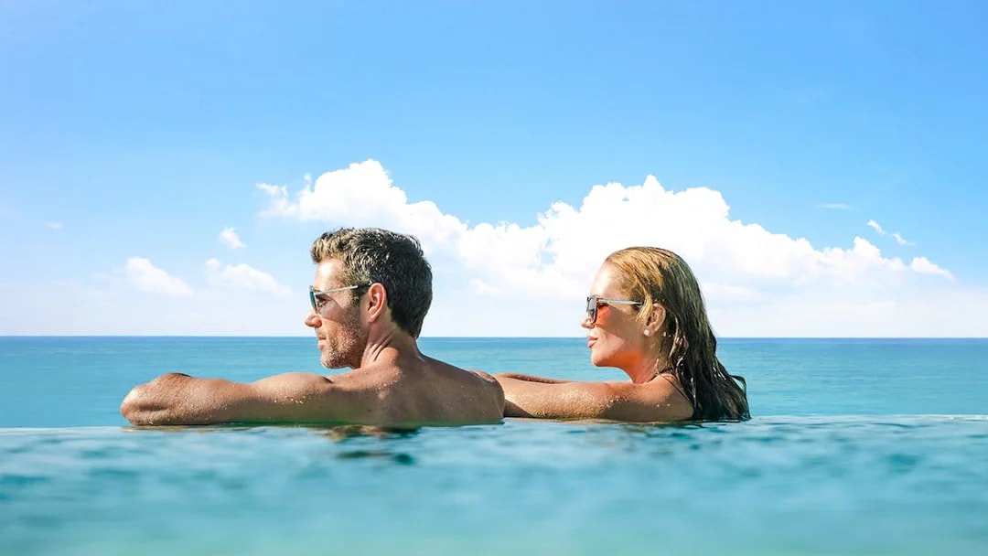 Guests relaxing in an infinity pool overlooking the ocean.