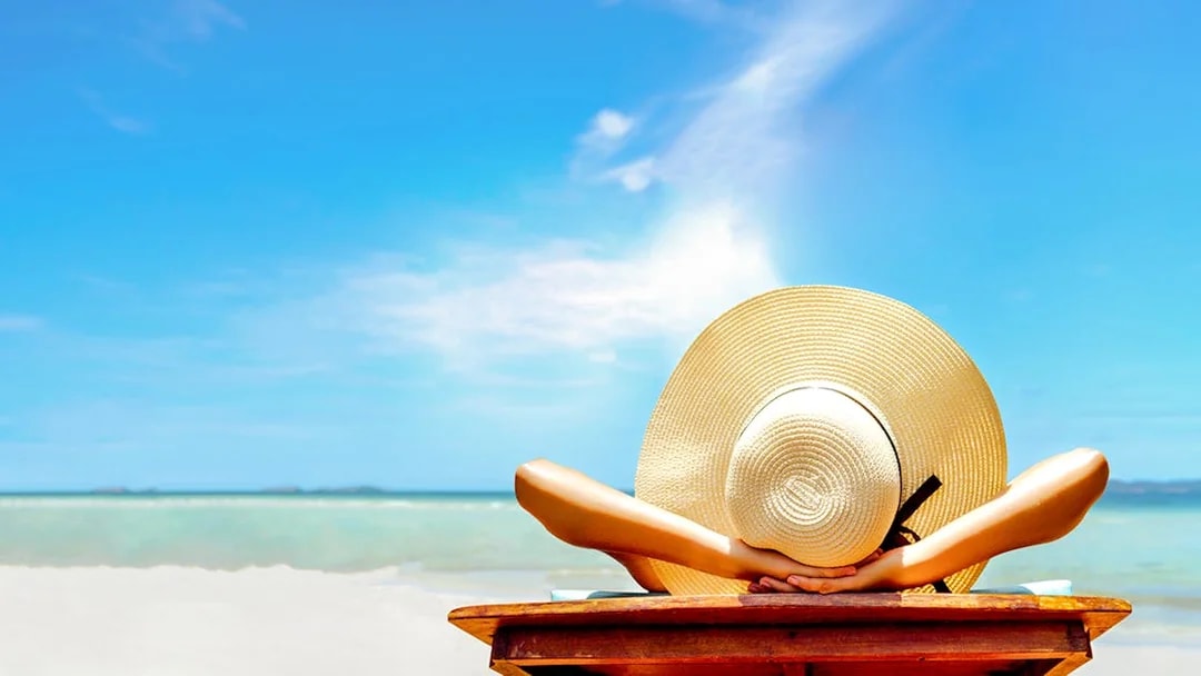 Person relaxing on a beach chair with a sun hat, overlooking the ocean in Bimini, Bahamas.