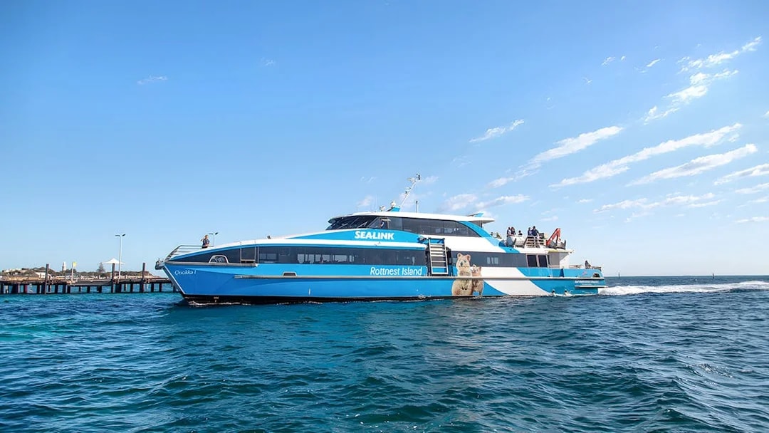 Ferry to Rottnest Island with tourists on deck, coastline visible in background.