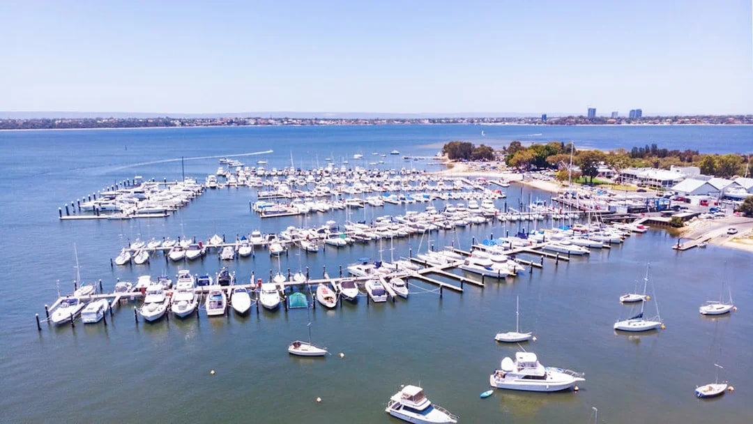 Boats docked at Royal Perth Yacht Club marina with city skyline in the background.