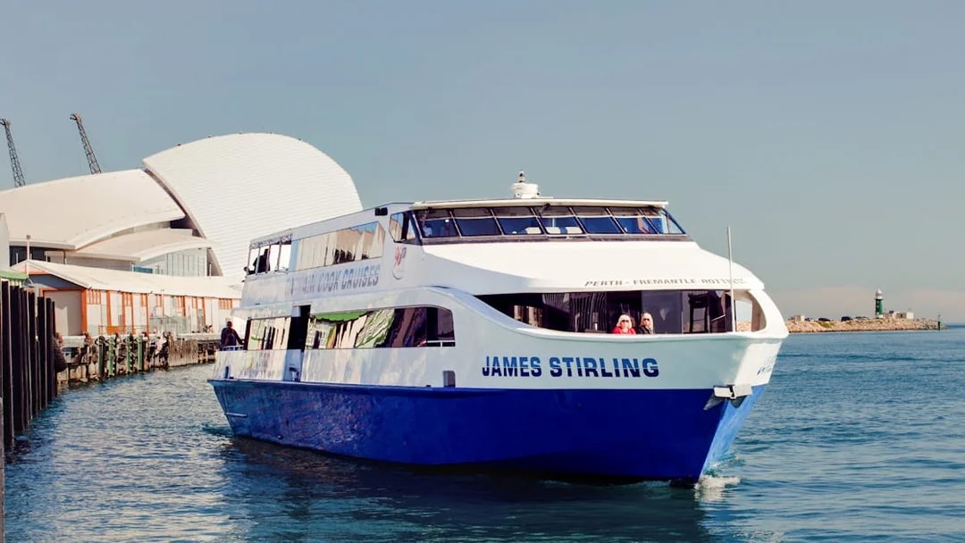 Cruise boat on Perth's Swan River near waterfront buildings.