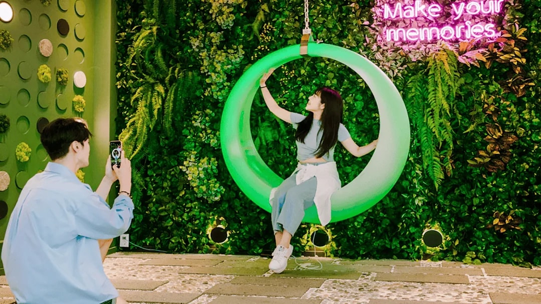 Couple enjoying Gangchon Gimnyujeong Rail Bike with neon sign backdrop.