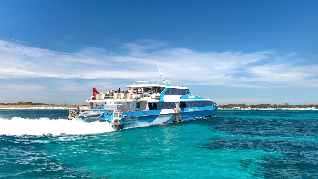Tourists on a ferry near Rottnest Island with coastline view, part of the guided bus tour.