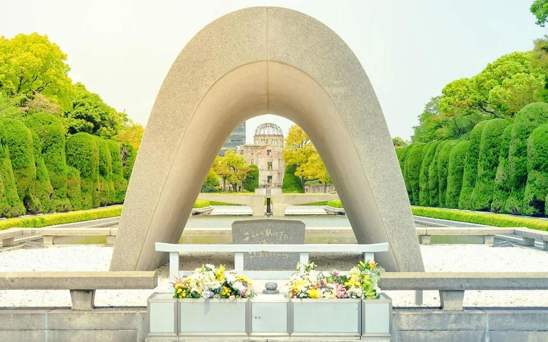 Hiroshima Peace Memorial Park cenotaph with Atomic Bomb Dome in background, Japan.