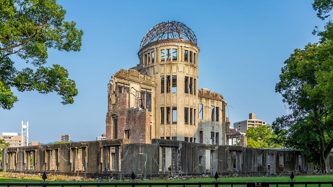 Atomic Bomb Dome at Hiroshima Peace Memorial Park, surrounded by trees and cityscape.