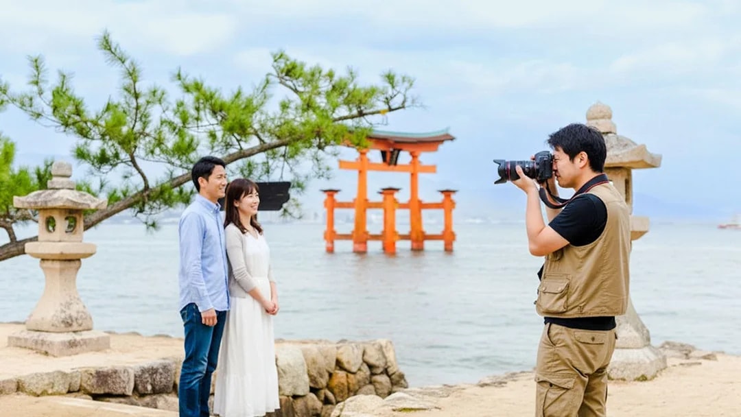 Photographer capturing a couple near the Torii gate at Miyajima, Japan.