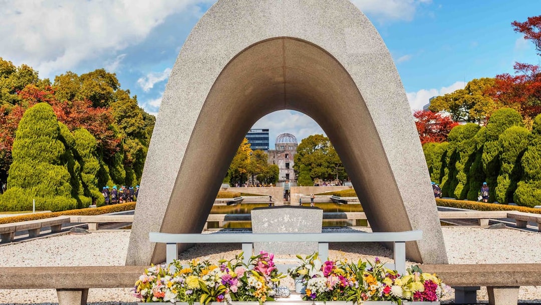 Hiroshima Peace Memorial Park cenotaph with Atomic Bomb Dome in background.