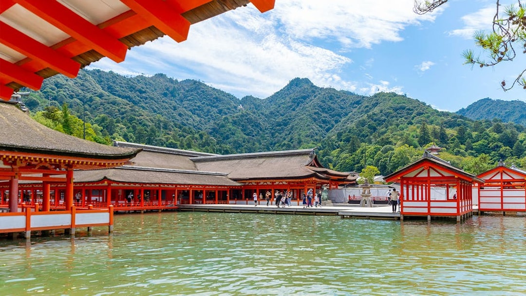 Itsukushima Shrine on Miyajima Island with mountains in the background, part of Hiroshima and Miyajima 1 Day Bus Tour.