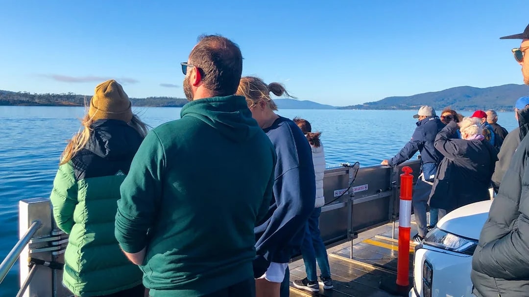 Tourists on a boat enjoying views of Bruny Island's coastline from Hobart.