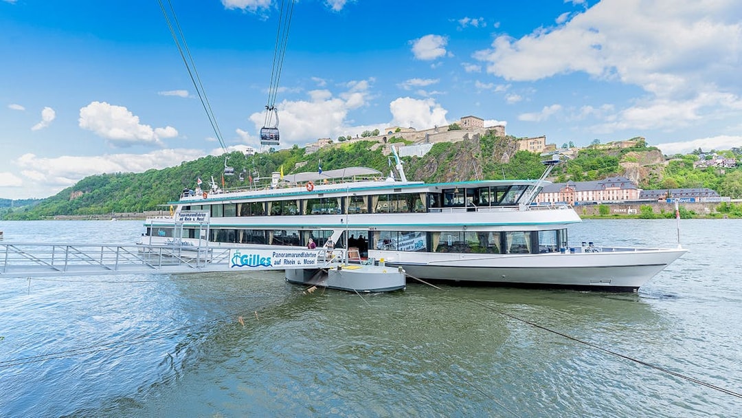 Koblenz sightseeing cruise boat on the Rhine River with Ehrenbreitstein Fortress in the background.