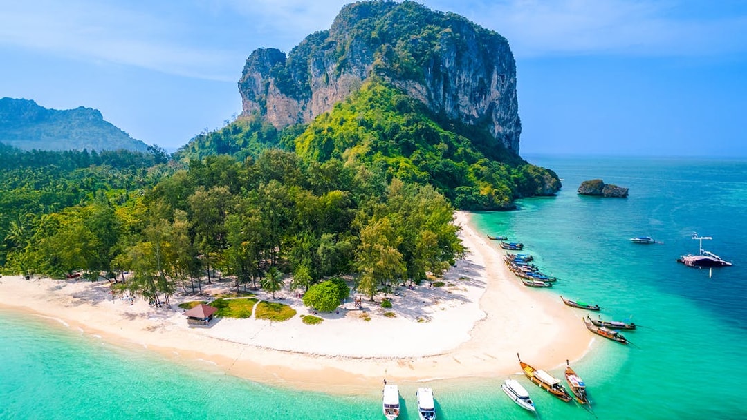 Aerial view of Ko Poda Island with sandy beach and boats in turquoise water, Thailand.