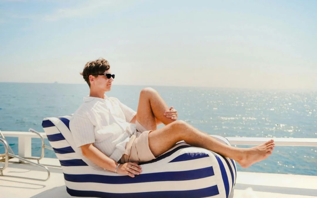 Tourist relaxing on a longtail boat deck with ocean view.