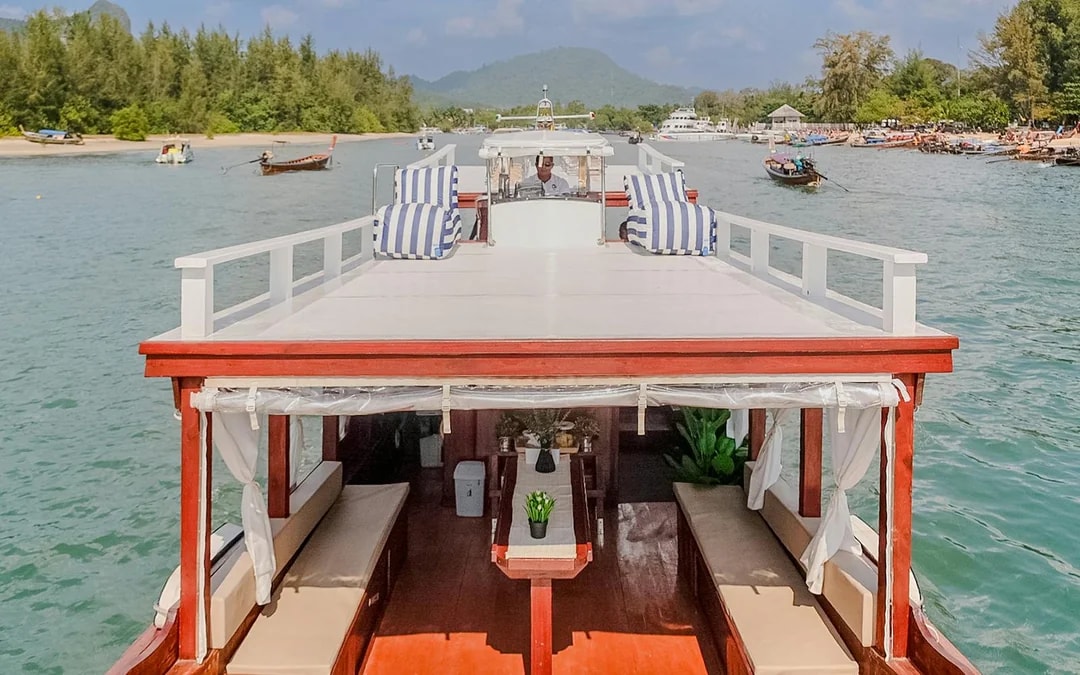 Upper deck of a long tail boat in Krabi with striped cushions and scenic view.