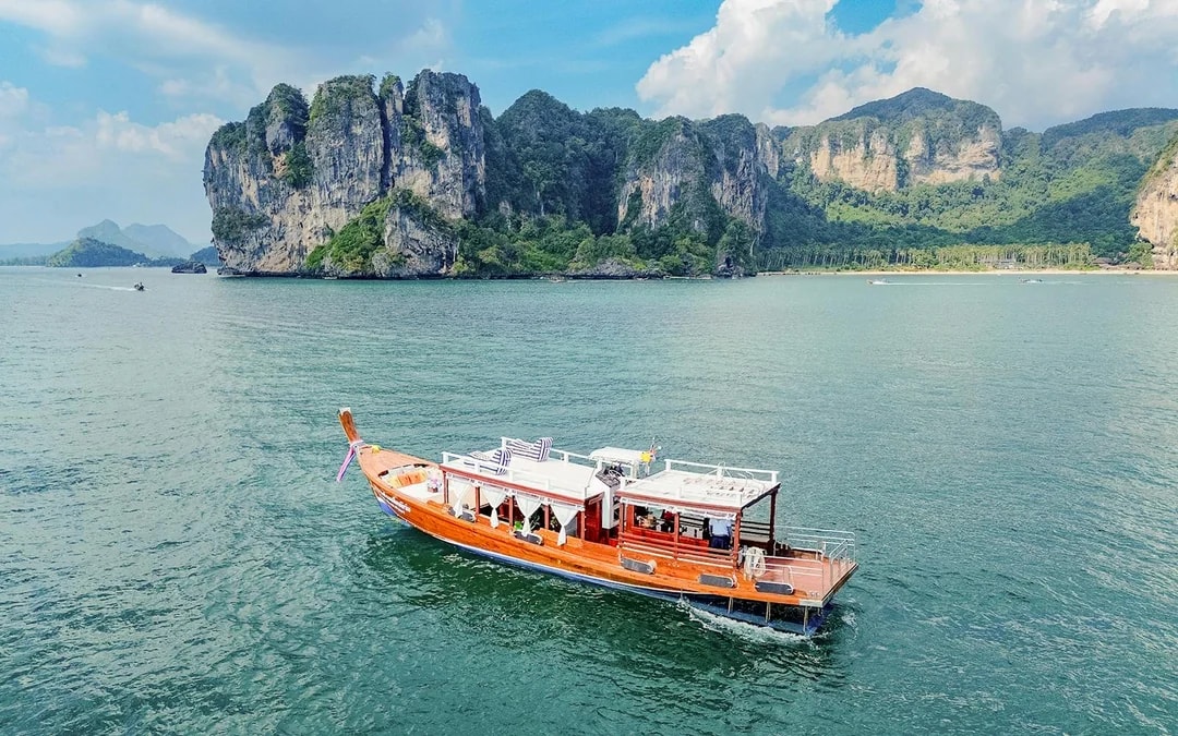 Long tail boat on the water near limestone cliffs, Ko Hong, Thailand.