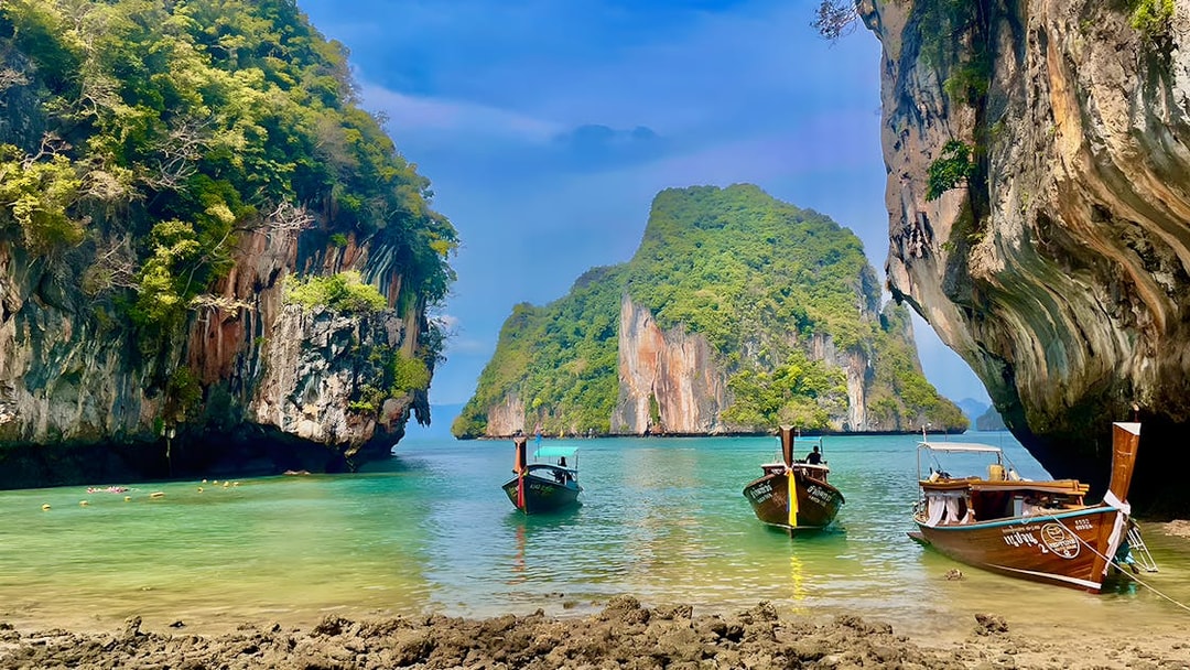 Speed boats anchored near limestone cliffs on Krabi Hong Island, Thailand.