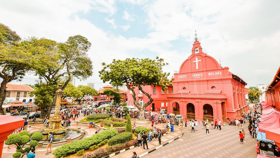 Christ Church Melaka with tourists exploring the historical site on a Melaka tour from Kuala Lumpur.