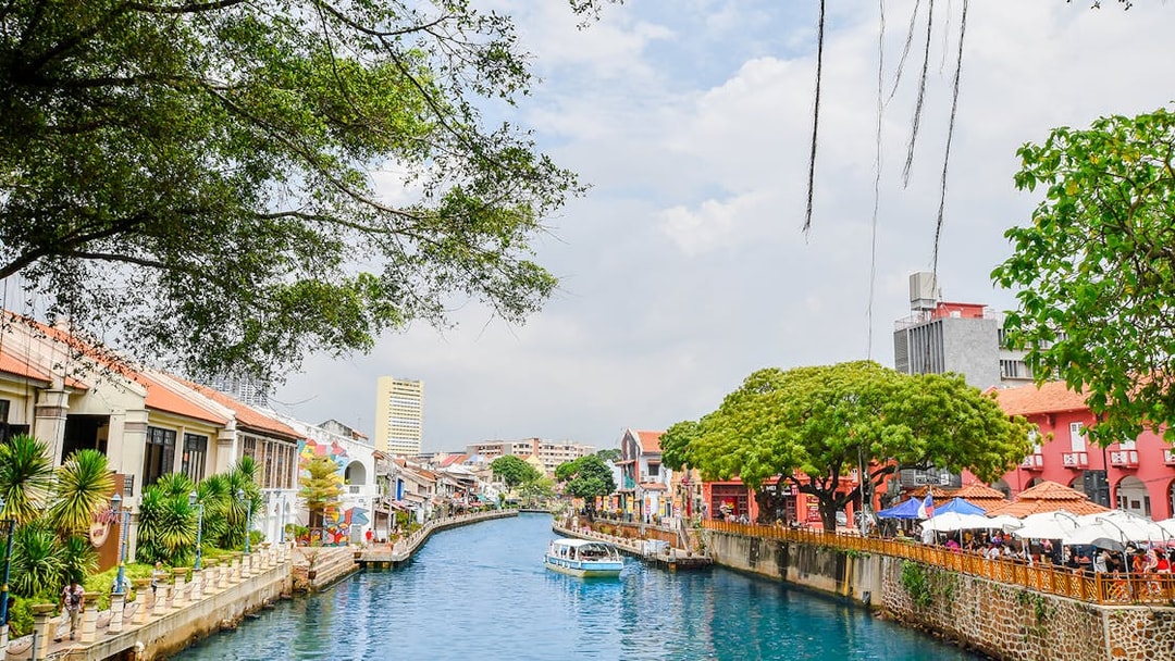 Melaka River with colorful buildings and a boat, part of the Historical Melaka Tour from Kuala Lumpur.