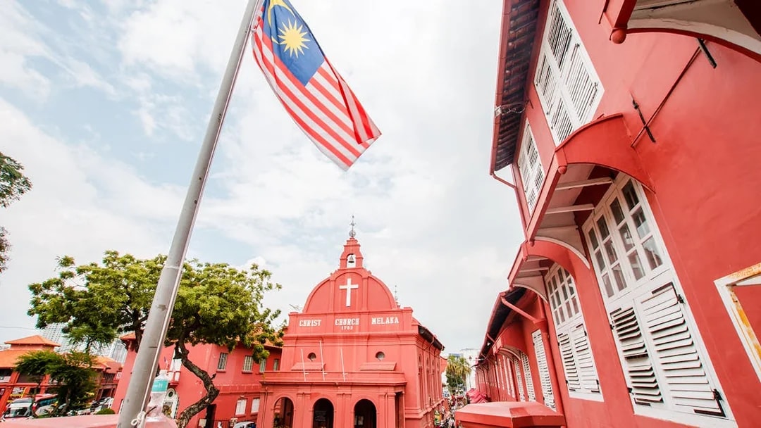 Christ Church Melaka with Malaysian flag, part of Historical Melaka Tour from Kuala Lumpur.