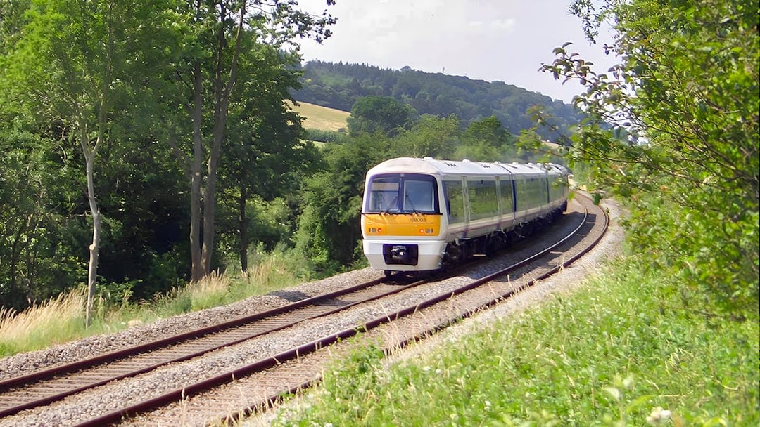Train traveling through lush countryside near Warwick Castle.