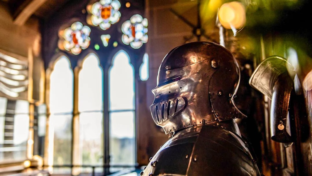Knight's armor inside Warwick Castle with stained glass window in the background.