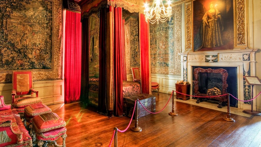 Warwick Castle bedroom with ornate canopy bed, tapestries, and fireplace.