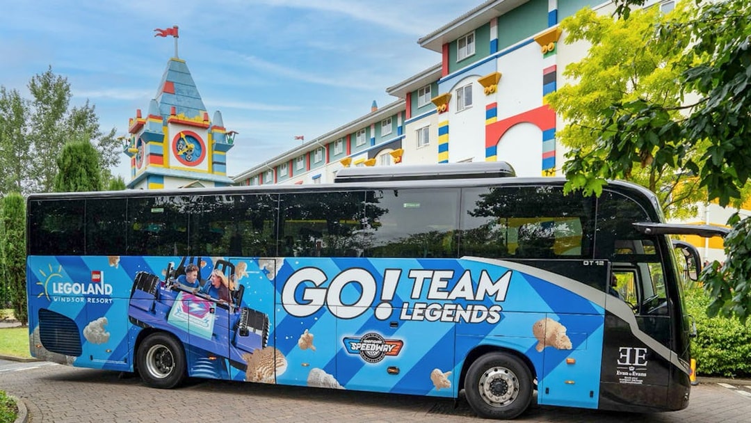 LEGOLAND® Windsor Resort Express bus parked near colorful hotel building.
