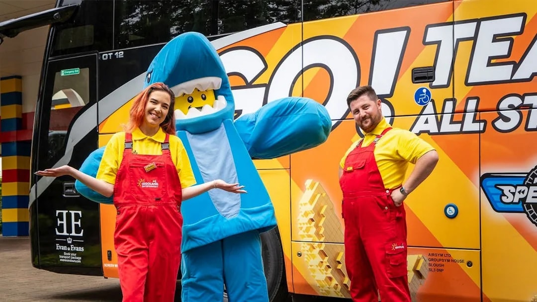 LEGOLAND® Windsor Resort staff and mascot in front of themed bus for London express tour.