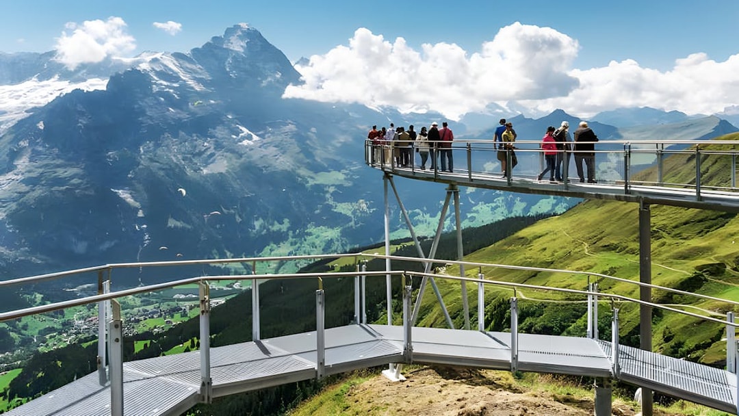 Tourists on viewing platform at Grindelwald First with mountain views.