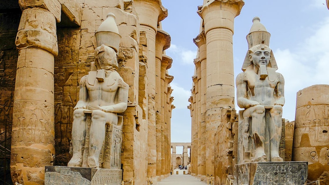 Giant statues at Karnak Temple in Luxor, Egypt, flanked by ancient columns.