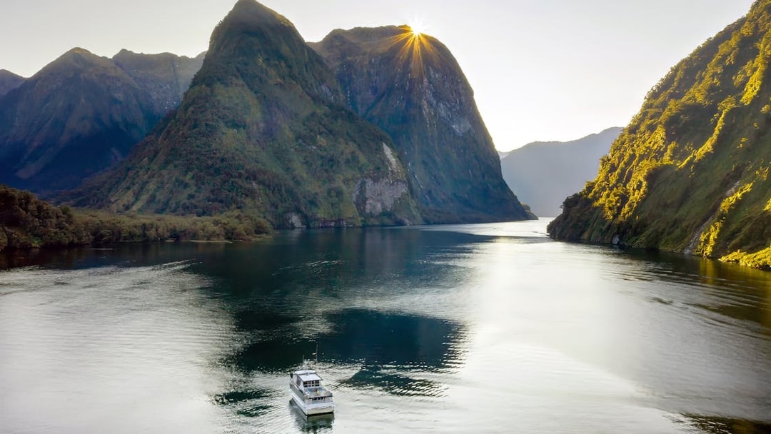 Cruise boat on Doubtful Sound with sunlit mountains, Manapouri, New Zealand.