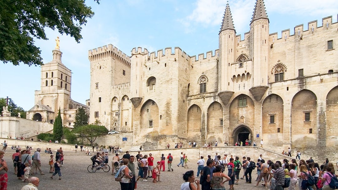 Palace of the Popes in Avignon with tourists exploring the historic site.