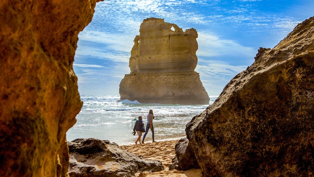 Tourists walking on Gibson Steps beach with rock formations, Great Ocean Road tour.
