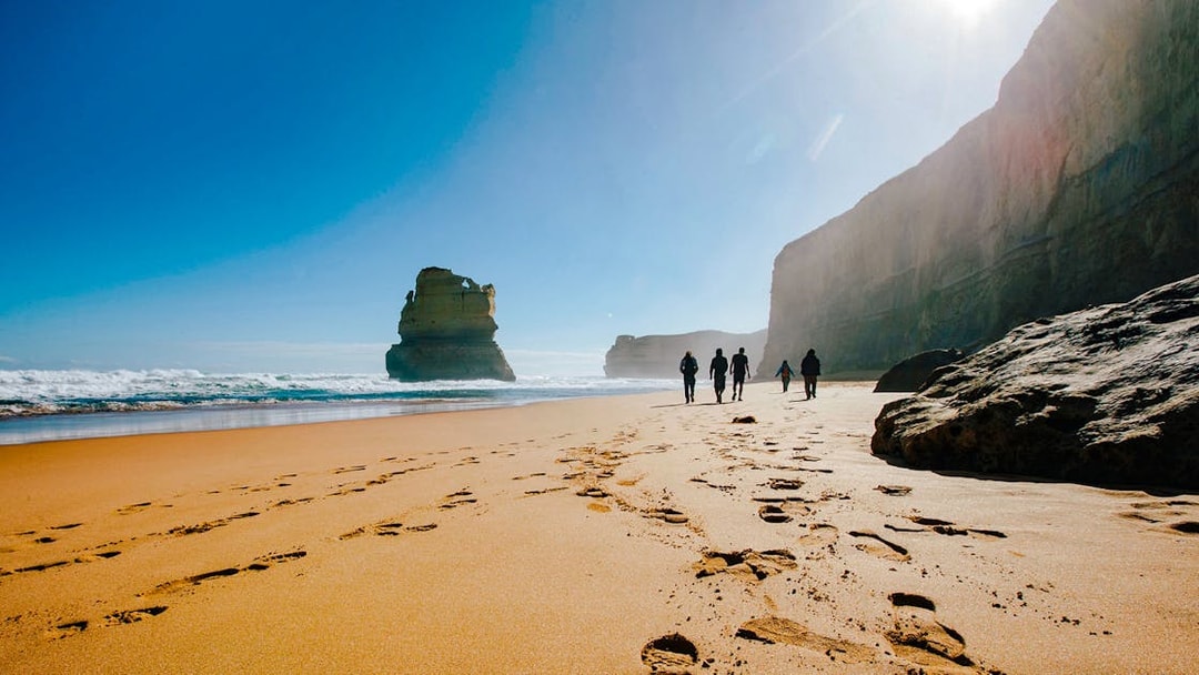 Tourists walking along Gibson Steps beach on the Full Day Great Ocean Road Guided Tour.