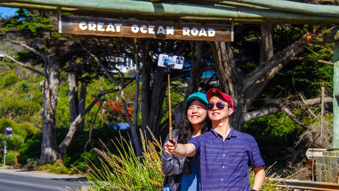 Tourists taking a selfie at the Great Ocean Road memorial arch.