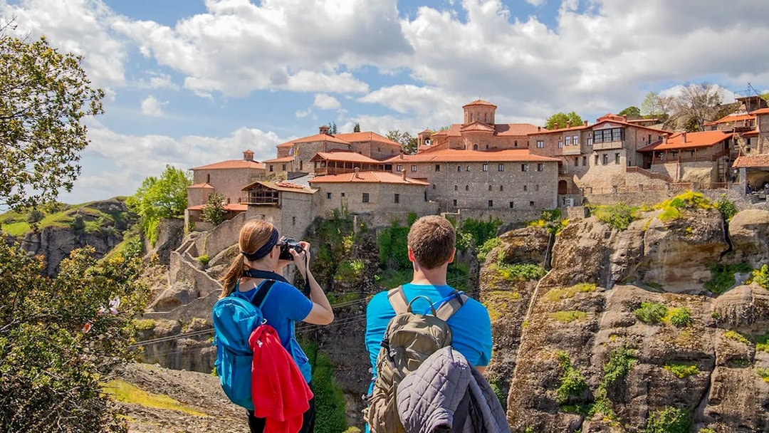 Guests hiking near Meteora monastery, Greece, capturing scenic views.