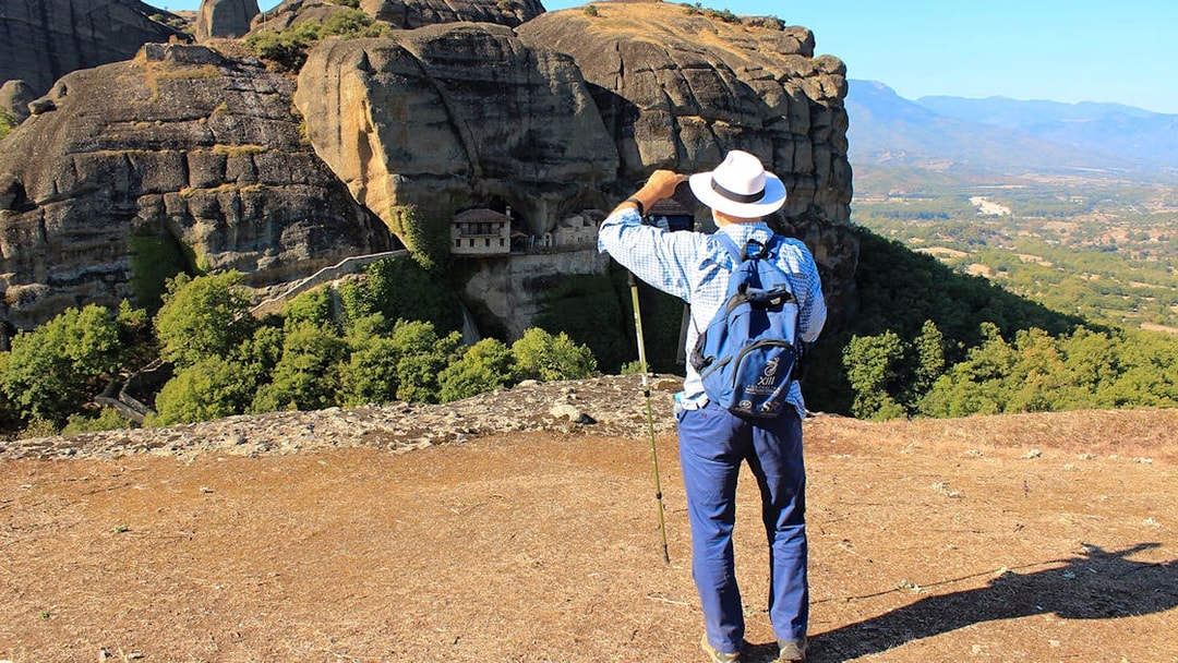 Guest hiking with view of Meteora rock formations and monastery in Greece.