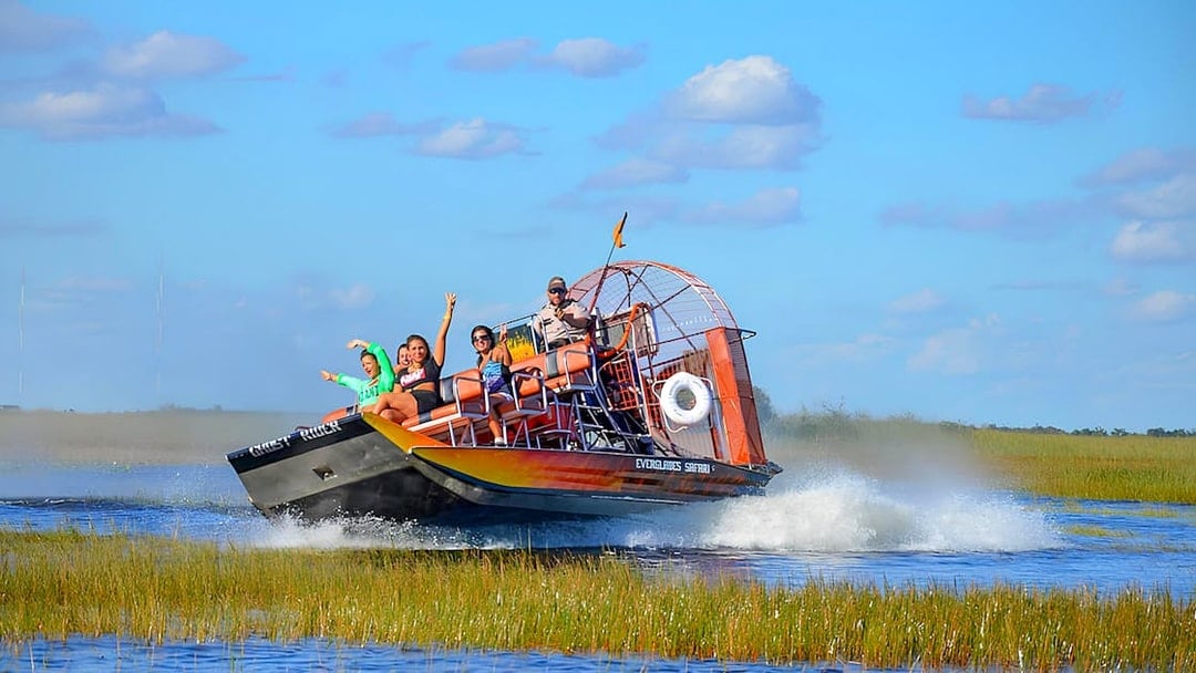 Airboat tour in Everglades Safari Park with passengers enjoying the ride, Miami.