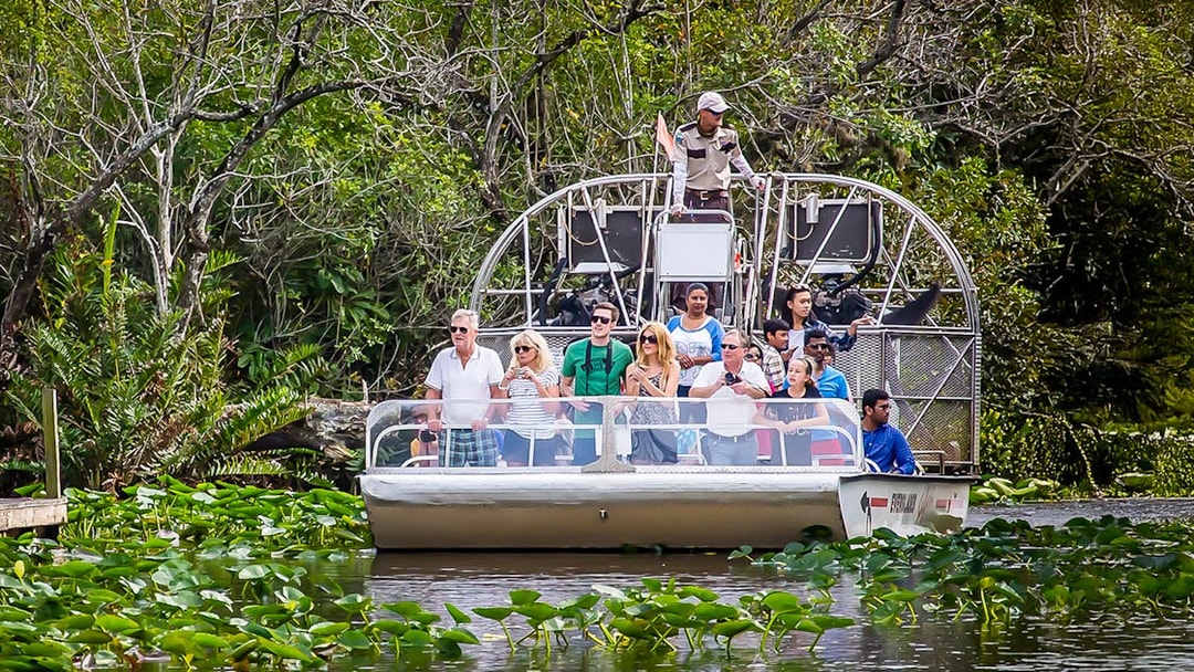 Airboat tour in Everglades Safari Park with group observing wildlife, Miami transfer included.