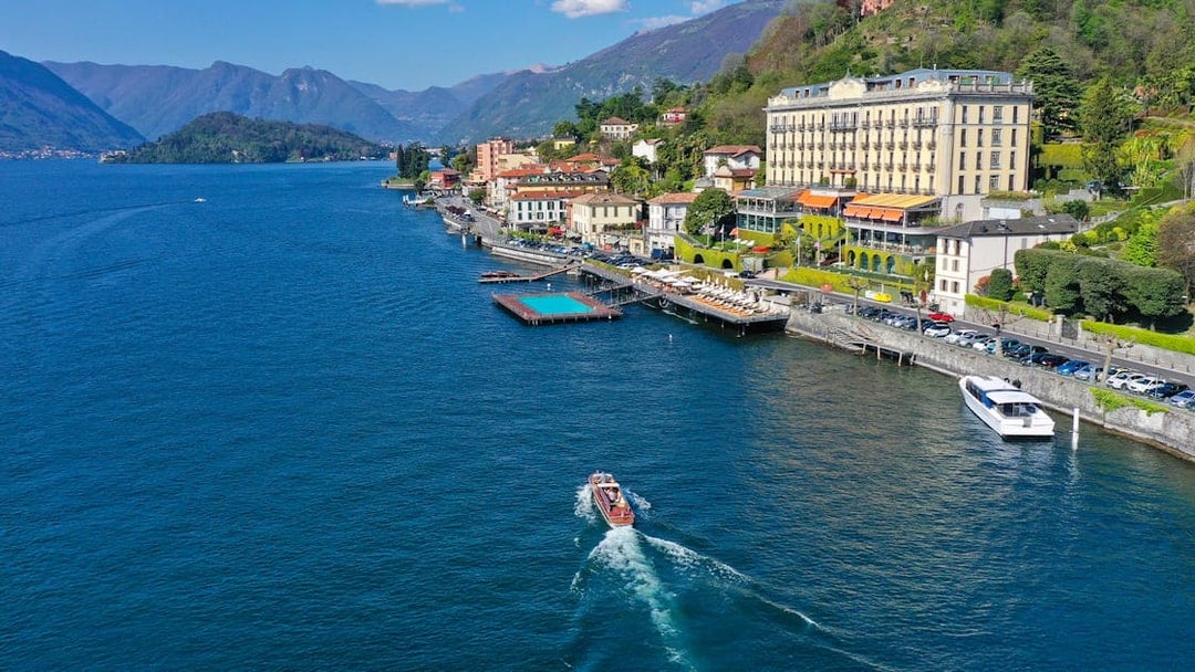 Aerial view of Lake Como with a boat near the shoreline and mountains in Lombardy, Italy.