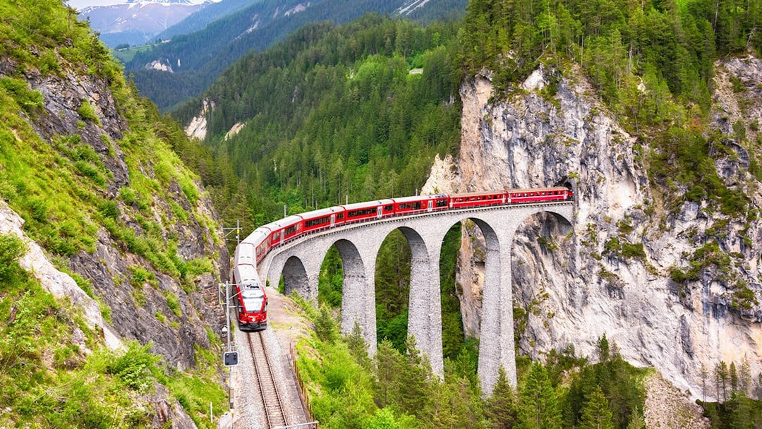 Bernina Train crossing a stone viaduct in the Swiss Alps.