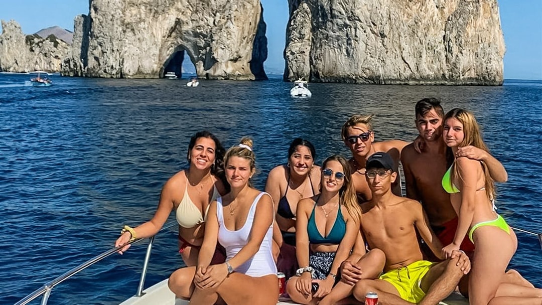 Group enjoying boat tour near Faraglioni rocks, Capri.
