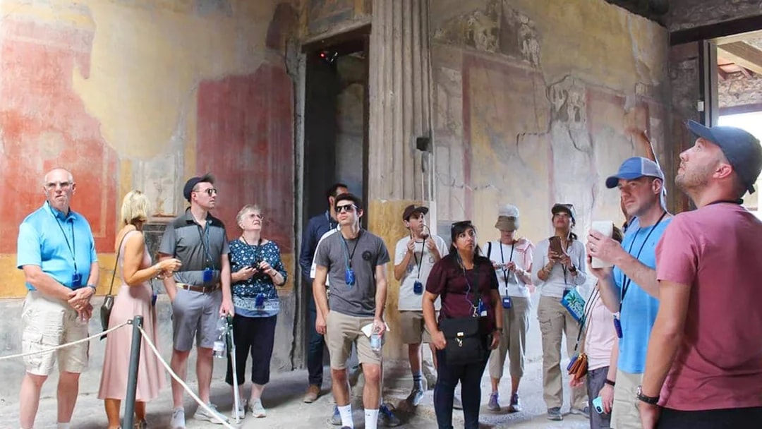 Tour group exploring ancient frescoes in Pompeii on a guided half-day tour from Naples.